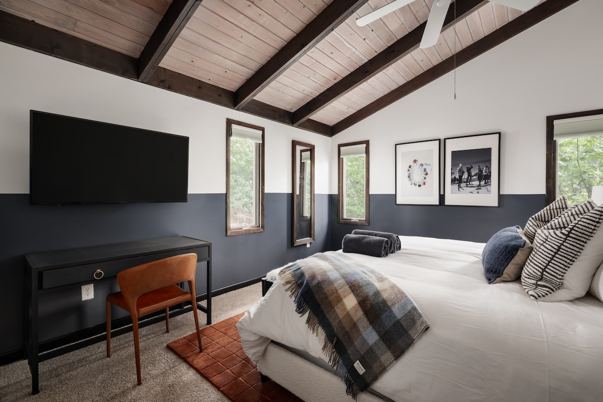 Bedroom with king bed and bunk beds beneath a vaulted ceiling